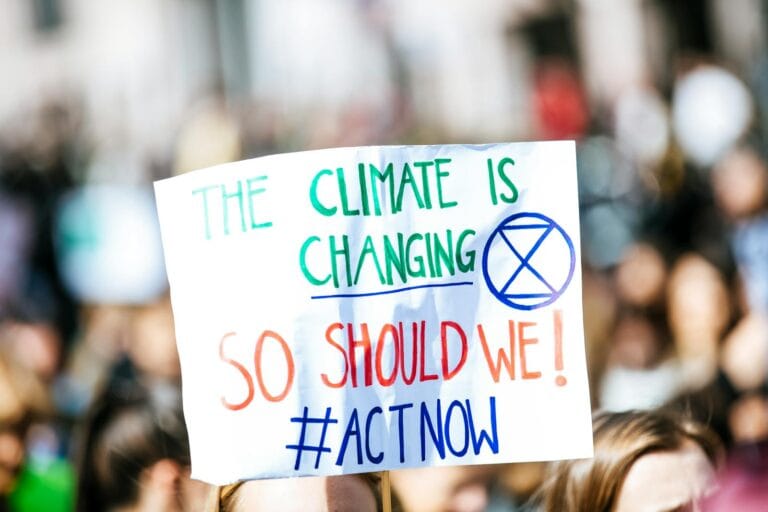 Crowd gathering for climate change protest, holding activist sign. by pexel