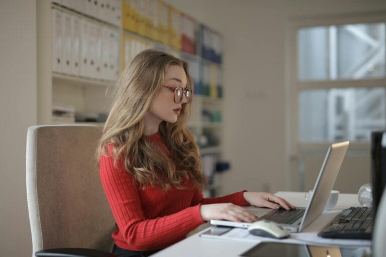 A dedicated female freelancer working on a laptop from her home office. Greenhouse Gas (GHG) accounting