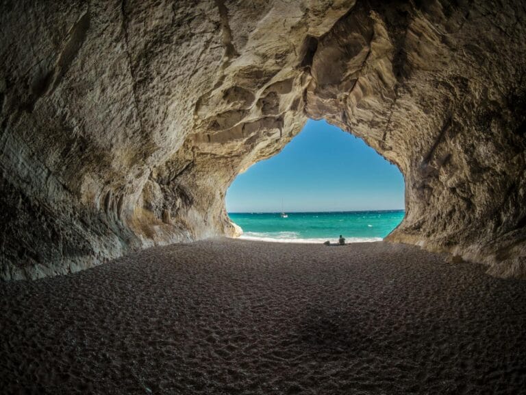 Discover a peaceful beach scene framed by a natural cave formation, perfect for relaxation. blue carbon.