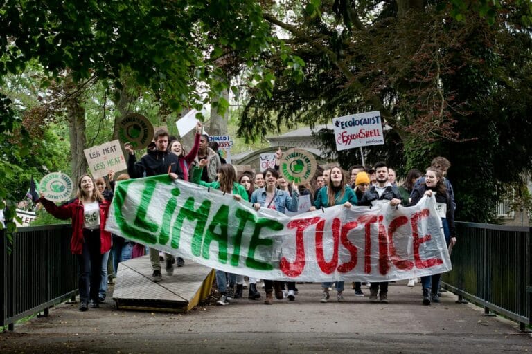 Group of activists marching for climate justice in Maastricht with banners and signs. climate justice.