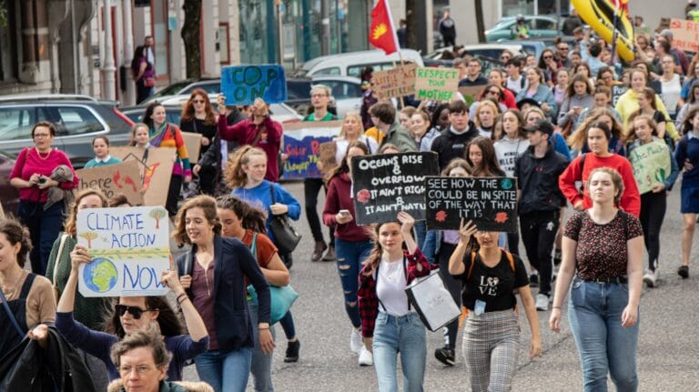 A vibrant climate march with diverse group holding signs demanding climate action. cop30.