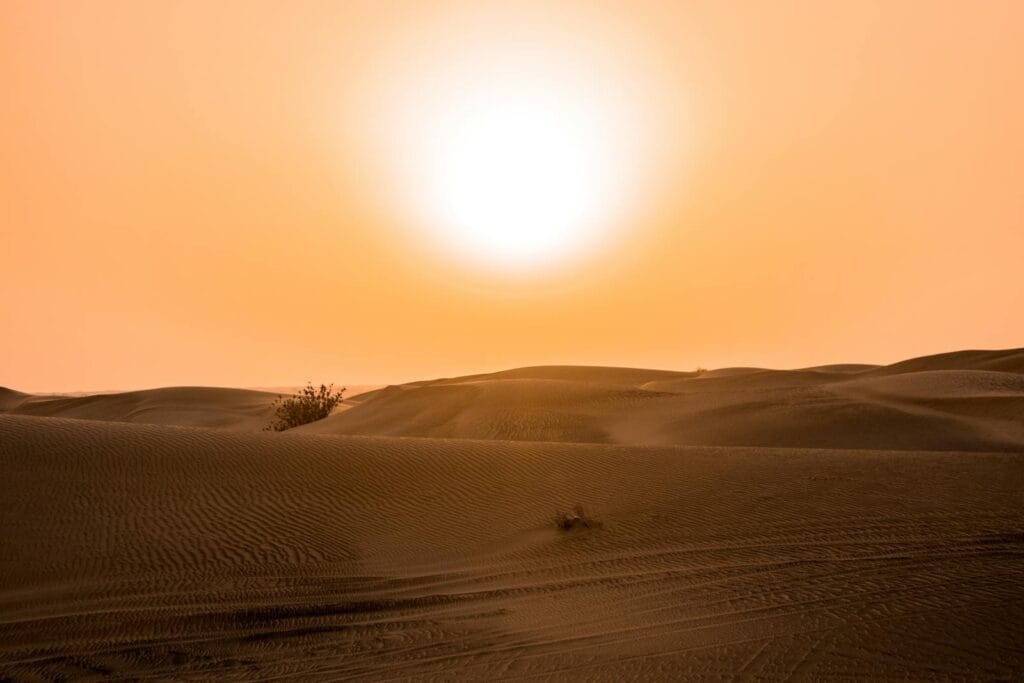 Scenic view of the sun setting over sand dunes in the Dubai desert.