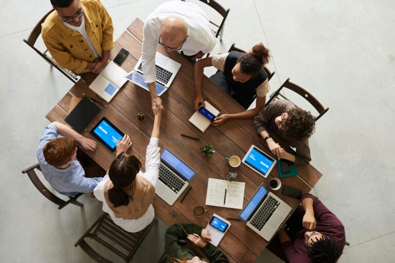 A business team meeting with laptops and tablets reflects collaboration in sustainability report analysis and ESG implementation.